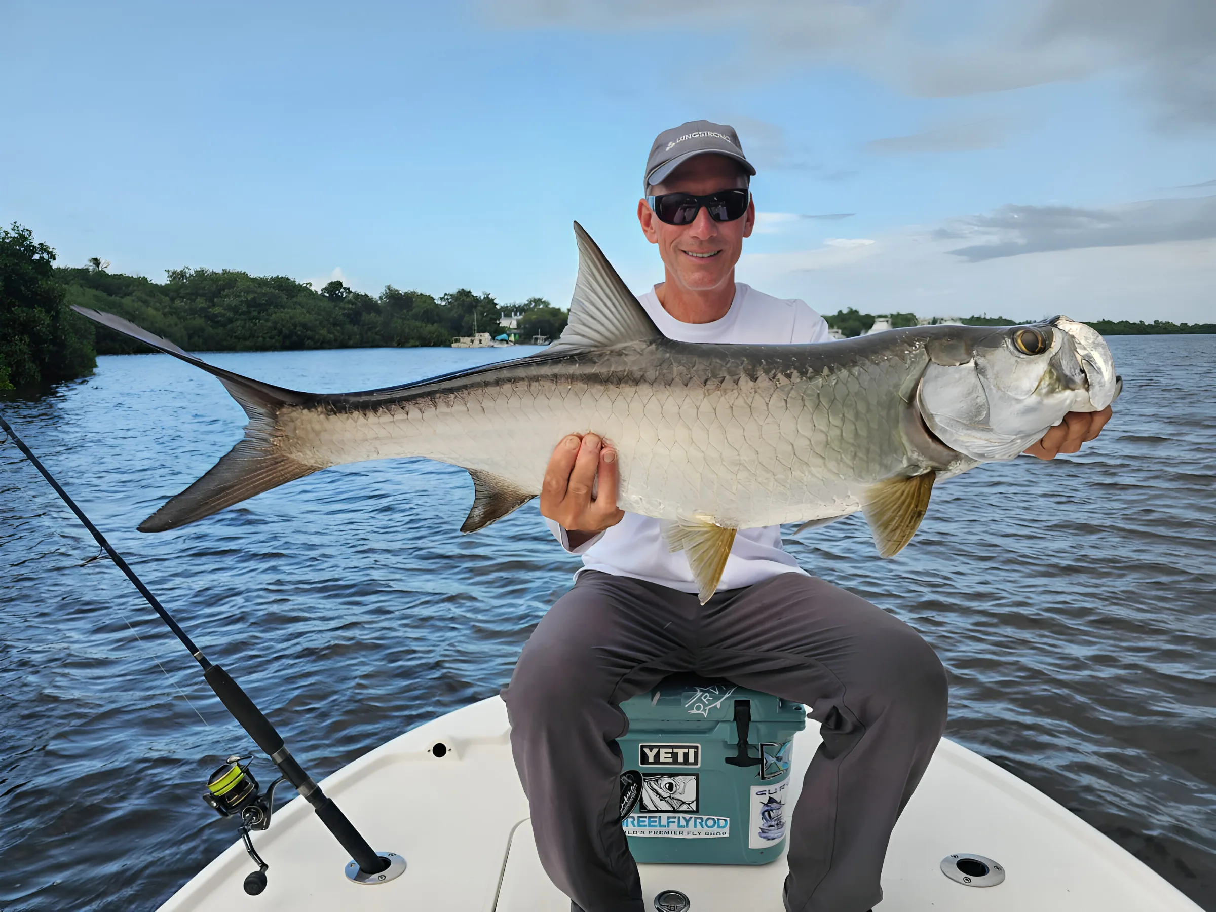 Angler holding a huge silver tarpon aboard the Reel Addiction charter boat on Laguna San José